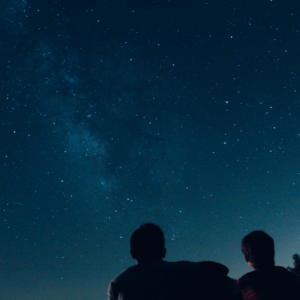 Two heads are silhouetted against a blue starry sky.