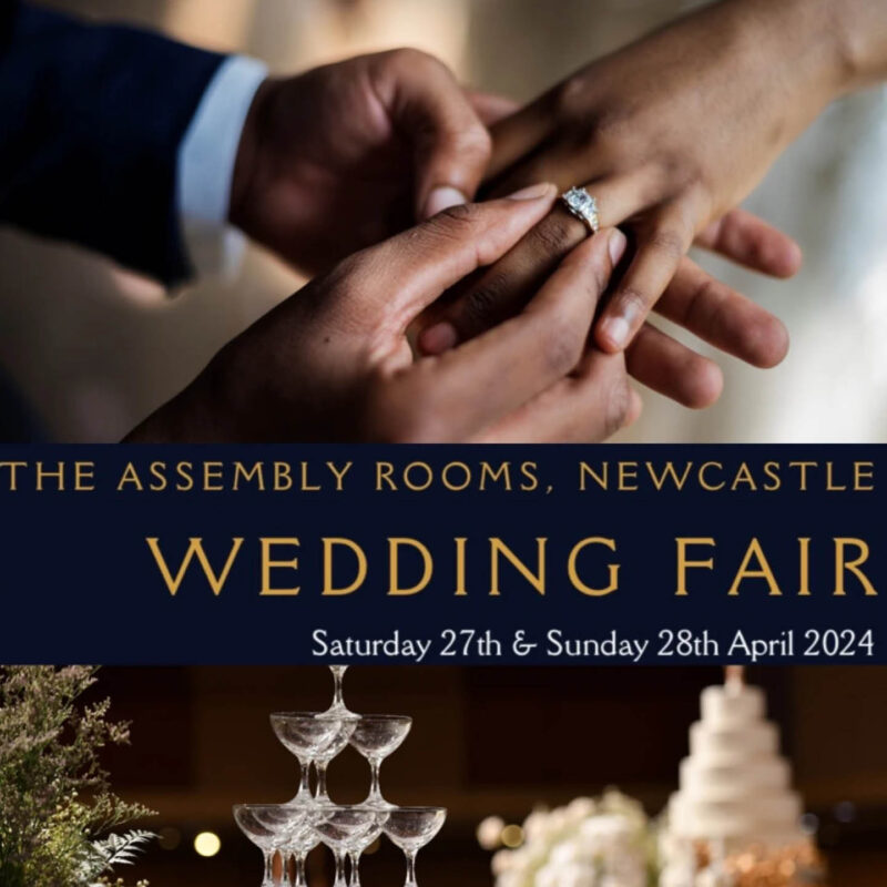 A groom pushes a diamond ring onto the bride's finger. Gold text against a blue strip says: The Assembly Rooms Newcastle Wedding Fair.