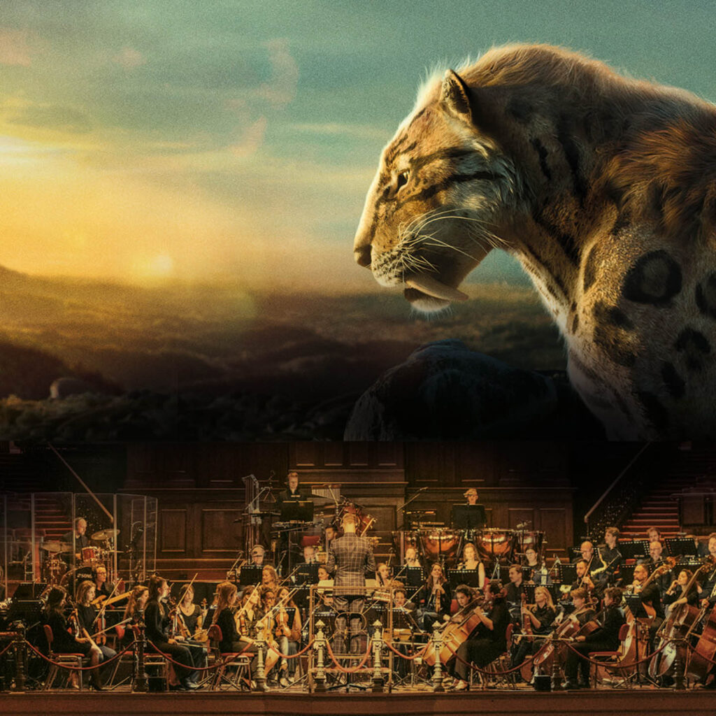A huge wild cat stands sidelong against a sunset sky. Below it, a tiny orchestra play their instruments.