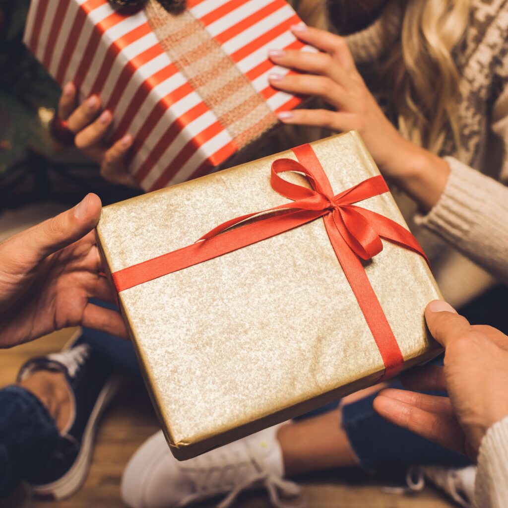 Two wrapped Christmas presents are being exchanged between a coupl