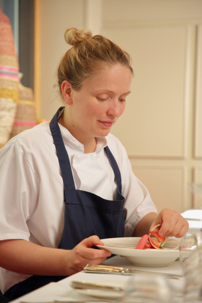 Pastry chef Helen Doyle a young women with blonde hair is perfecting a plate wearing an apron