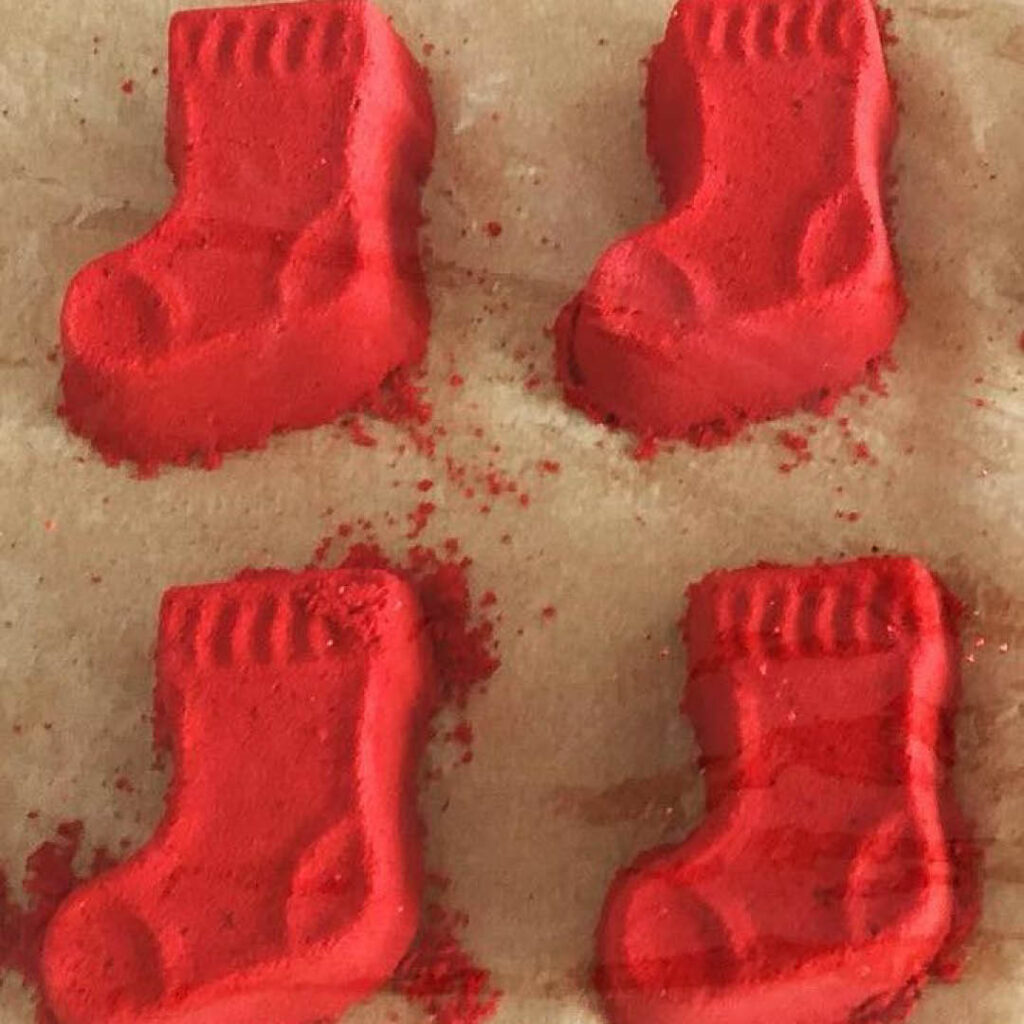 Four red bath bombs shaped like Christmas stockings. They are an example of what you can make at the Shipley Art Gallery's Christmas bath bomb workshop.