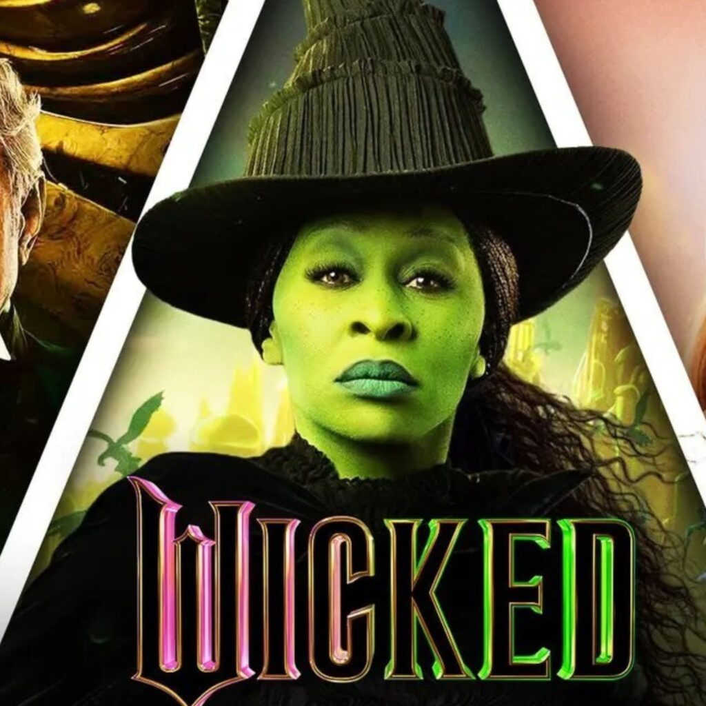 Elphaba, the witch in Wicked, stares straight at the camera. Pink and green text overlays the image with the film title: Wicked.