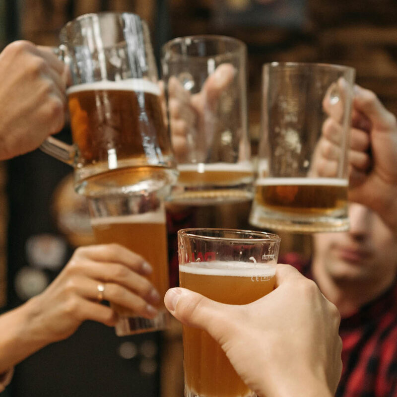 A group of people raise their pint glasses and clink them together on a pub tour.