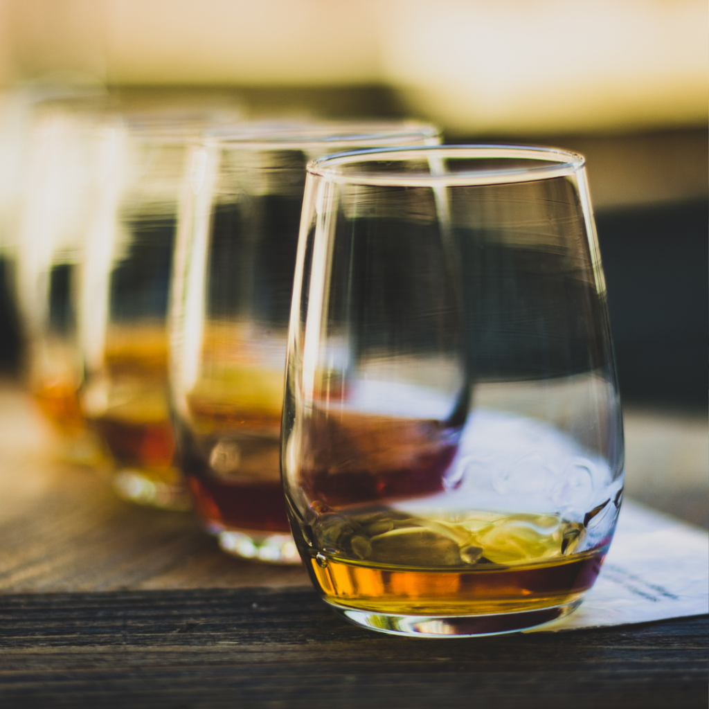 A row of glasses containing a small amount of whisky for tasting.