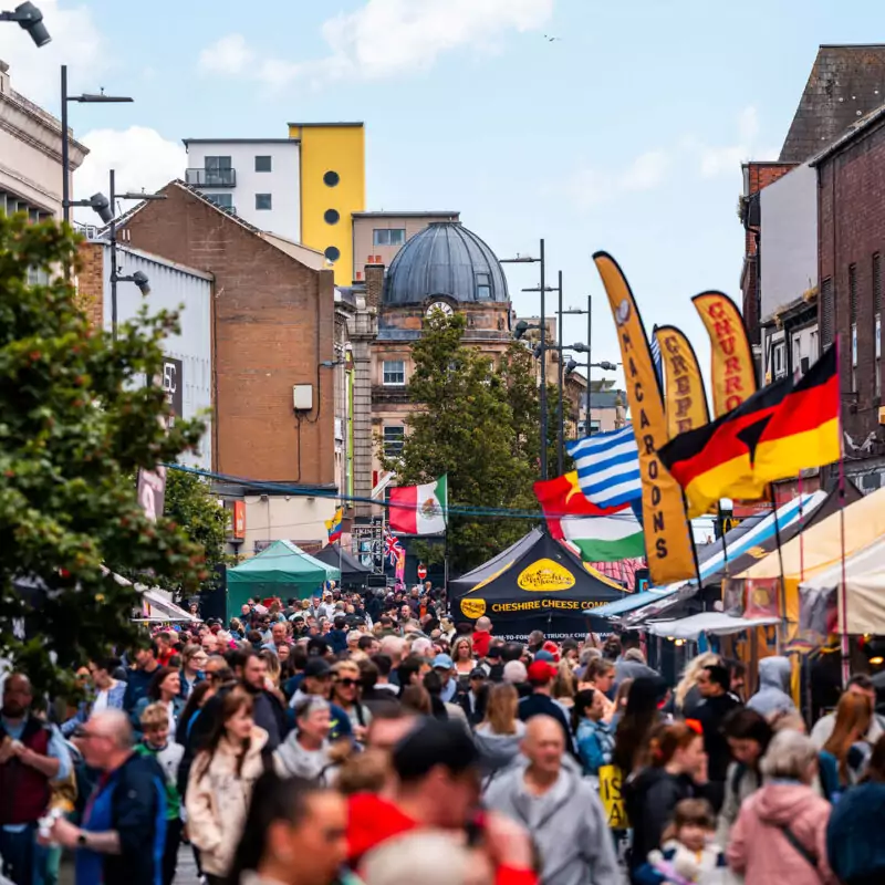 Swarms of people fill a street in Sunderland. Coloured gazebos and flags can be seen in the distance. They belong to the various food traders at Sunderland Food and Drink Festival.